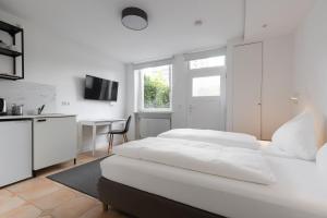 a white bedroom with two beds and a desk at Davin City Aparments - Self-Check-In in Hamburg