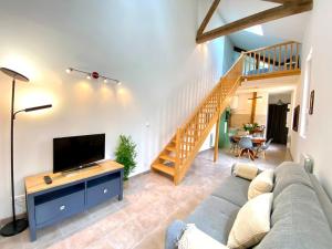 a living room with a couch and a flat screen tv at Le secret du Morvan in Saulieu