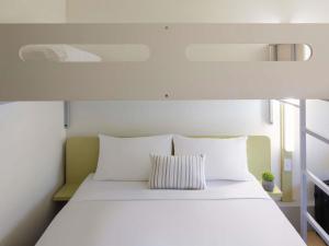 a bed with white sheets and pillows in a room at ibis Budget Brisbane Airport in Brisbane