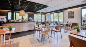 a dining room with tables and chairs in a restaurant at Campanile NATURE - Bordeaux Sud Pessac in Pessac