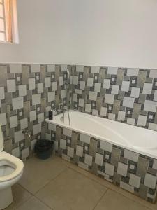 a bathroom with a bath tub and a toilet at Suzie's Nest 2 in Lilongwe +14 photos