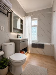a bathroom with a toilet and a sink and a window at All residence in Almaty +16 photos