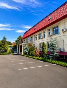 a building with a red roof and a parking lot at All residence in Almaty