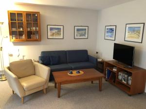 a living room with a couch and a chair and a tv at Ferienwohnung-Silvie-8 in Westerland