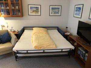 a bed in a room with a couch and a tv at Ferienwohnung-Silvie-8 in Westerland