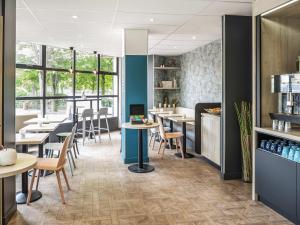 a restaurant with tables and chairs and windows at ibis Styles Sceaux Paris Sud in Sceaux