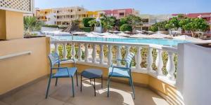 a balcony with two chairs and a swimming pool at Servatur Isora Suites in Puerto de Santiago