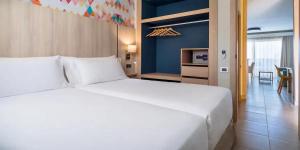 a bedroom with a large white bed and a living room at Servatur Isora Suites in Puerto de Santiago