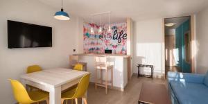 a living room with a table and yellow chairs at Servatur Isora Suites in Puerto de Santiago