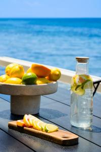a bowl of lemons and a bottle of water and a cutting board at Elysian Seaside Suite in Skala Kallirachis