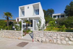 a white house with a stone wall at House Nika in Punat