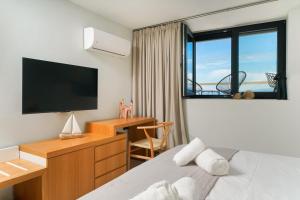 a bedroom with a bed and a desk with a television at Elysian Seaside Suite in Skala Kallirachis