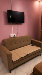 a brown couch in a room with a flat screen tv at Thaanya Guest Rooms in Chinchwad