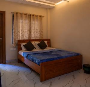 a bedroom with a bed with blue sheets and a window at Thaanya Guest Rooms in Chinchwad