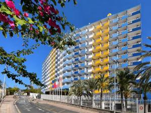 a tall building with yellow windows and palm trees at Hotel Cabana in Benidorm