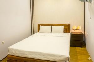 a bedroom with a bed with white sheets and two lamps at Anh Duong Hotel in Noi Bai