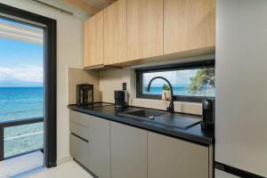 a kitchen with a sink and a window with the ocean at Elysian Seaside Suite in Skala Kallirachis +56 photos