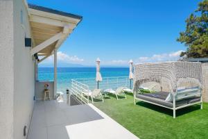 a porch with a swing and chairs and the ocean at Elysian Seaside Suite in Skala Kallirachis