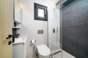 a bathroom with a toilet and a glass shower at Elysian Seaside Suite in Skala Kallirachis