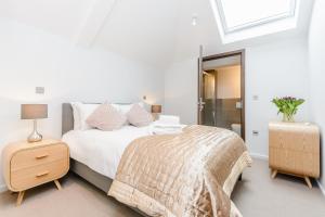 a white bedroom with a bed and a night stand with a lamp at Ibis House by Viridian Apartments in Richmond