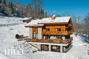 a wooden house with snow on the roof at Chalet Alya by HILO Collection in Les Allues