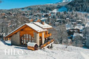 a building covered in snow with a mountain in the background at Chalet Alya by HILO Collection in Les Allues