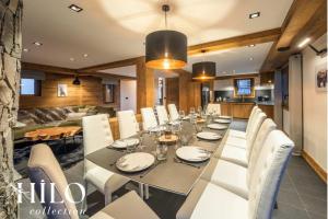 a dining room with a long table and white chairs at Chalet Alya by HILO Collection in Les Allues