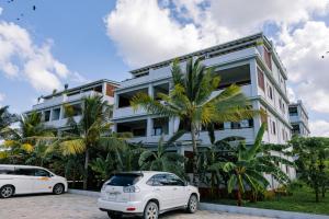 two white cars parked in front of a building at Castle Residence by Aura Space in Paje