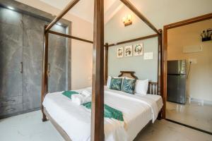 a bedroom with a four poster bed and a shower at Aloha Kai Modern Chic 2BHK Benaulim in Benaulim