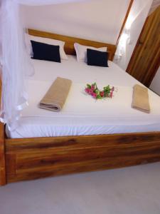 a bed with two towels and flowers on it at Beach Cab Resort in Arugam Bay
