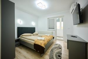 a small bedroom with a bed and a desk at Apartament Aleea Școlii in Haţeg