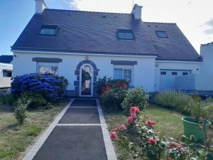 a white house with flowers in the yard at De l'ar mor bihan in Riantec