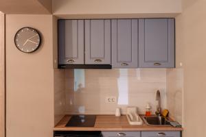a kitchen with white cabinets and a clock on the wall at Hotel Cocó in Timişoara