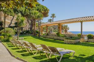 eine Reihe von Liegestühlen in einem Park in der Unterkunft Eden Roc Hotel & Spa by Brava Hoteles in Sant Feliu de Guixols