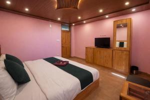 a bedroom with a bed and a flat screen tv at The Sana Cottge, Manali - Affordable Luxury Stay in Manali in Manāli