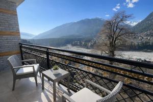 a balcony with chairs and a table and a view at The Sana Cottge, Manali - Affordable Luxury Stay in Manali in Manāli