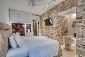 a bedroom with a white bed and a stone wall at Nalia Suites in Nafplio