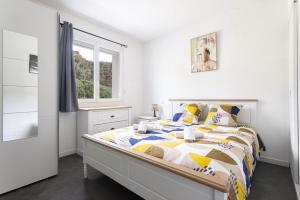 a white bedroom with a bed and a window at L'interlude in Amélie-les-Bains-Palalda