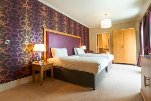 a bedroom with a large bed and a purple wall at Farington Lodge Hotel in Preston +54 photos