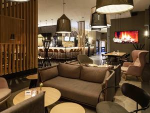 a lobby with a couch and tables and chairs at ibis Styles Vechta in Vechta