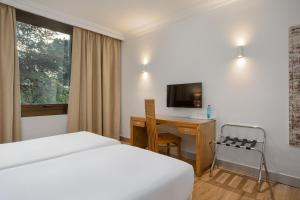 a hotel room with a bed and a desk and a television at Hotel Eden Park by Brava Hoteles in Riudellots de la Selva
