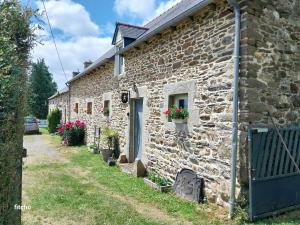 an old stone house with flowers in a yard at L'abreuvoir du Leffo in Allineuc