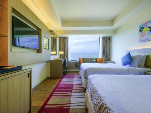 a hotel room with two beds and a window at Mercure Penang Beach in George Town