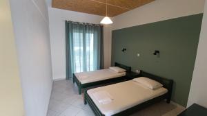 two beds in a room with a window at Ferouli Residence in Rizá