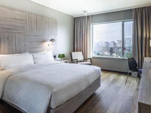 a hotel room with a large bed and a large window at Pullman Santiago Vitacura in Santiago
