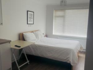 a bedroom with a bed and a table and a window at Studio - Sleeps 2 - Wifi - Parking in Dunstable +3 photos