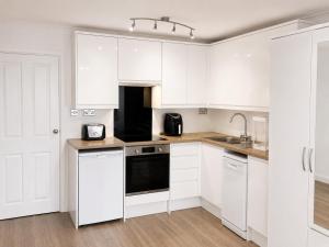 a white kitchen with white cabinets and a sink at Studio - Sleeps 2 - Wifi - Parking in Dunstable