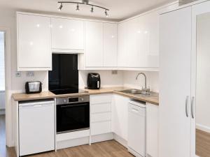 a white kitchen with white cabinets and a sink at Studio - Sleeps 2 - Wifi - Parking in Dunstable