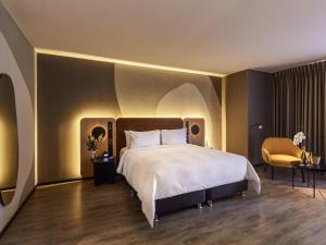 a bedroom with a large white bed and a chair at Pullman Lima San Isidro in Lima +218 photos