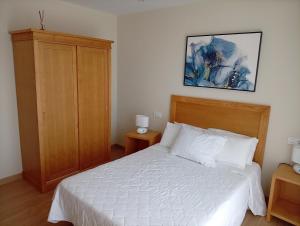 a bedroom with a white bed and a wooden cabinet at Casa Da Ponte in Lobios